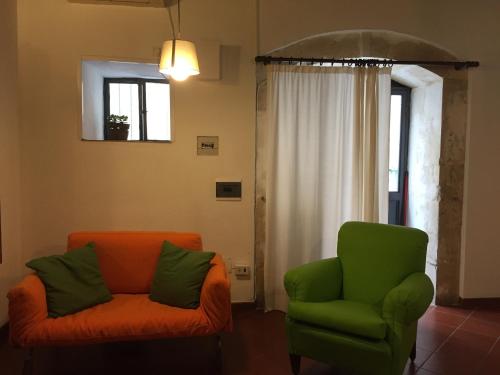 シラクーサにあるAppartamento Blue Noteのリビングルーム(オレンジ色のソファ、緑色の椅子付)