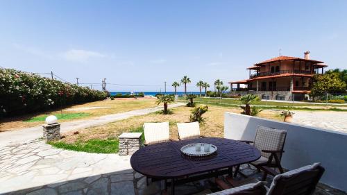 a patio with a table and chairs and a house at Anemos Deluxe Poseidi Apartments in Possidi
