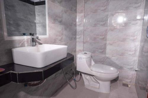 Łazienka z białą toaletą i umywalką w obiekcie Kim Chua Guest House w mieście Kâmpôt