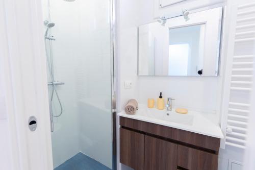 ein Bad mit einem Waschbecken, einem Spiegel und einer Dusche in der Unterkunft MARNE II - 3 PIÈCES - PARKING - Carré d'or Menton in Menton