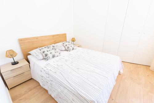 ein weißes Schlafzimmer mit einem Bett und Holzboden in der Unterkunft MARNE II - 3 PIÈCES - PARKING - Carré d'or Menton in Menton