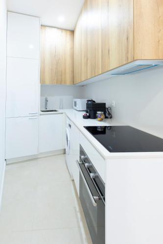 - une cuisine blanche avec des placards en bois et une cuisinière four supérieur dans l'établissement MARNE II - 3 PIÈCES - PARKING - Carré d'or Menton, à Menton