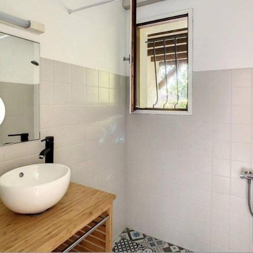 une salle de bain avec un lavabo blanc et une fenêtre dans l'établissement La maison près du Lac, à Aureilhan