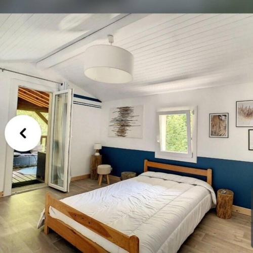 une chambre avec un grand lit avec un mur bleu dans l'établissement La maison près du Lac, à Aureilhan