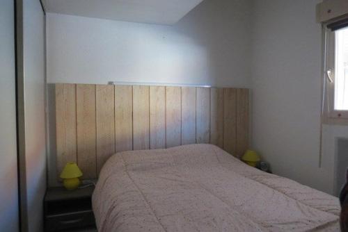 1 dormitorio con 1 cama con cabecero de madera en Agréable Maison Résidence au calme - terrasse- parking privé - 6ANI84 en Le Barcarès