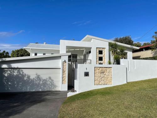 a white house with a garage at Magnolia Central Coffs Harbour in Coffs Harbour
