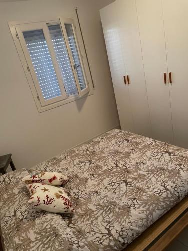 a bedroom with a bed with two pillows and a window at Cravellet 67 in Alghero