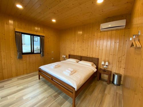 1 dormitorio con 1 cama en una pared de madera en Clouds Camping House, en Nanzhuang