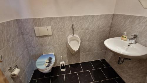 a bathroom with a sink and a toilet and a urinal at AMW Ferienwohnungen in Legau