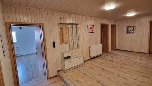 an empty room with wooden floors and a room with a door at AMW Ferienwohnungen in Legau