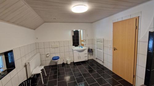a bathroom with a sink and a toilet and a door at AMW Ferienwohnungen in Legau