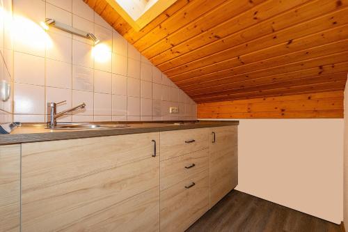 a kitchen with a sink and a wooden ceiling at Landhaus Braun in Mittenwald
