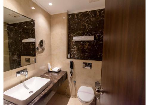een badkamer met een wastafel, een toilet en een spiegel bij The Grand Ambassador in Phagwara