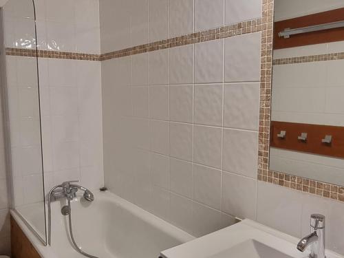 une salle de bain avec une baignoire, un lavabo et un miroir dans l'établissement Studio agréable aux pieds des pistes avec balcon et animaux tolérés - FR-1-181-2591, à Aime La Plagne