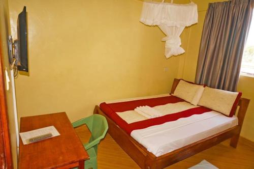 a small bedroom with a bed and a table at Mipeja Hotel in Busia