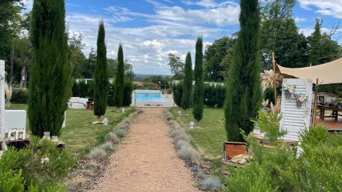 un camino a través de un jardín con árboles y una piscina en Le Domaine, en La Chapelle-de-Guinchay