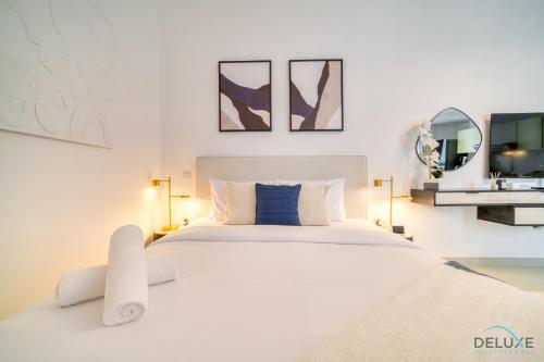 a white bedroom with a large white bed and two mirrors at Placid Studio at Afnan 4 Midtown Dubai Production City by Deluxe Holiday Homes in Dubai