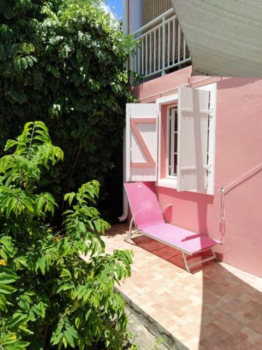 a pink chair sitting on the porch of a pink house at Dous'Inn Kreyol Appartement in Grand-Bourg