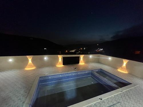 a swimming pool on the roof of a house at night at Gernatah Farm مزرعة غرناطه in Ajloun
