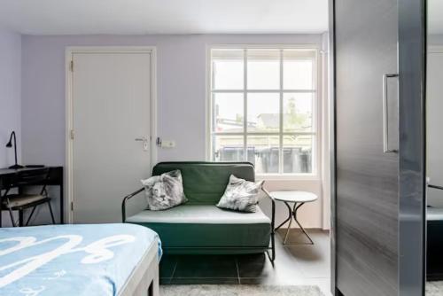 een slaapkamer met een groene bank en een raam bij Sky Villa in Bergschenhoek
