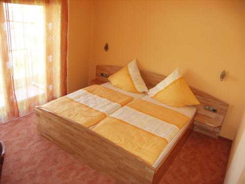 um quarto com uma cama com lençóis amarelos e uma janela em Gästehaus Stephanie em Ilbesheim