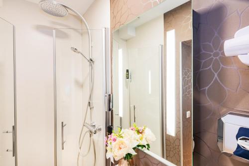 a bathroom with a shower and a vase of flowers at Hotel Fürst Garden in Dortmund