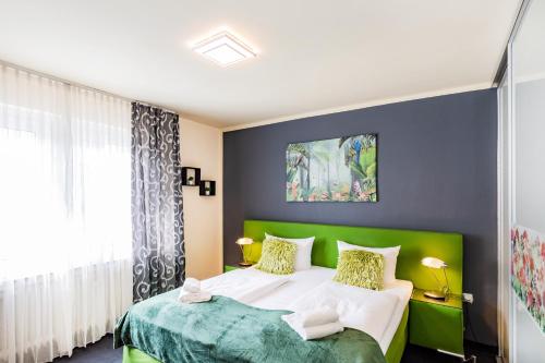 a bedroom with a green and white bed and a window at Hotel Fürst Garden in Dortmund