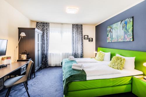 a hotel room with a green bed and a desk at Hotel Fürst Garden in Dortmund