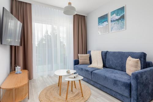 a living room with a blue couch and a table at Beach Apartments Perłowa Przystań Sztormowa by Renters in Sianozety