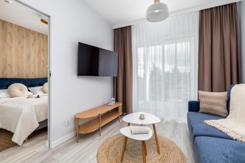 a living room with a bed and a blue couch at Beach Apartments Perłowa Przystań Sztormowa by Noclegi Renters in Sianozety