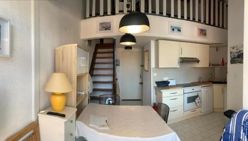 une cuisine avec une table avec une lampe et un escalier dans l'établissement T3 CLIMATISE 40m2 Piscine Parking PRIVE 2 Chambres Secteur falaises 50 m de la plage Proche centre-port 4 Personnes, au Cap d'Agde