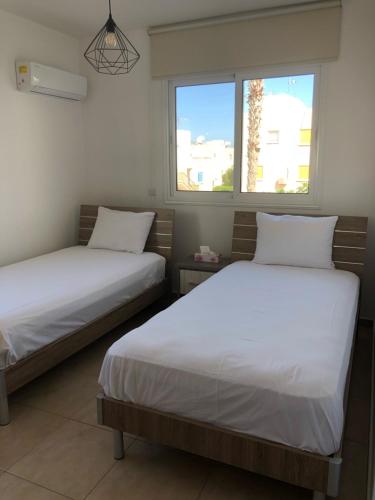 two beds in a room with two windows at Mythical Sands Resort - Maria in Protaras