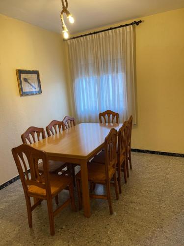 a dining room table with wooden chairs and a window at Mas del Llorenç in Ulldemolins
