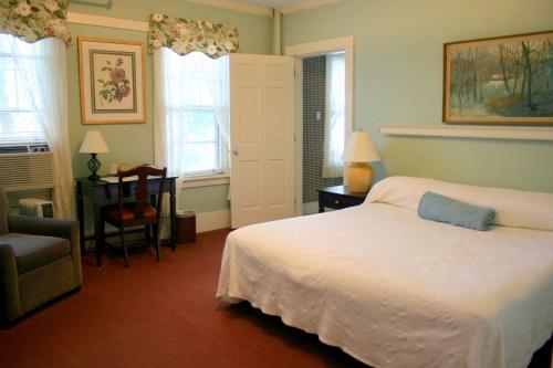 a bedroom with a bed and a chair and windows at Hotel Coolidge in White River Junction