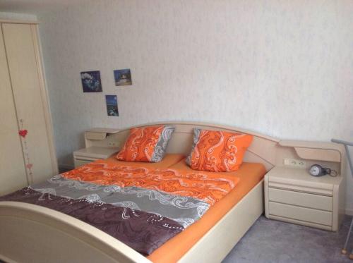 ein kleines Bett mit orangefarbenen Kissen in einem Zimmer in der Unterkunft Ferienwohnung Forstwiese in Großrosseln