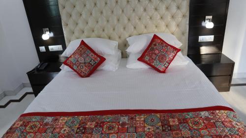a bedroom with a white bed with two red pillows at VENUS.HOTEL in Mohali