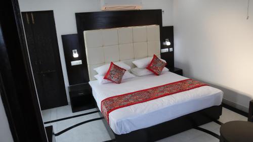 a bedroom with a large bed with red pillows at VENUS.HOTEL in Mohali