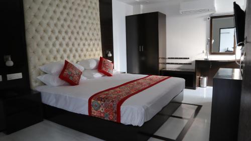 a bedroom with a large white bed with red pillows at VENUS.HOTEL in Mohali
