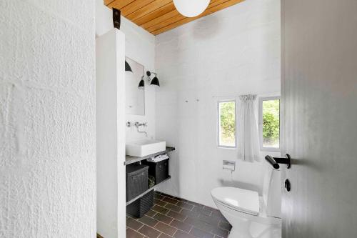 Baño blanco con aseo y lavamanos en Architect Designed Holiday Home With A Beautiful Sea View, en Gudhjem