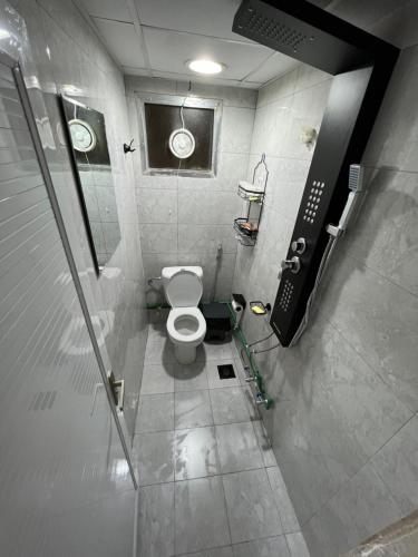 a small bathroom with a toilet in a stall at Dinar apartments - twin bed in Abu Dhabi