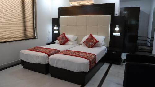a bedroom with a large bed with white sheets and red pillows at VENUS.HOTEL in Mohali