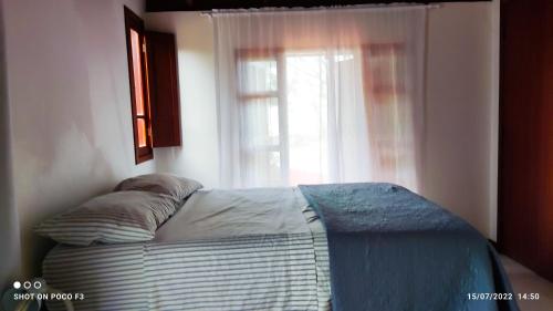 uma cama num quarto com uma janela em casa Encantadora em Florianópolis