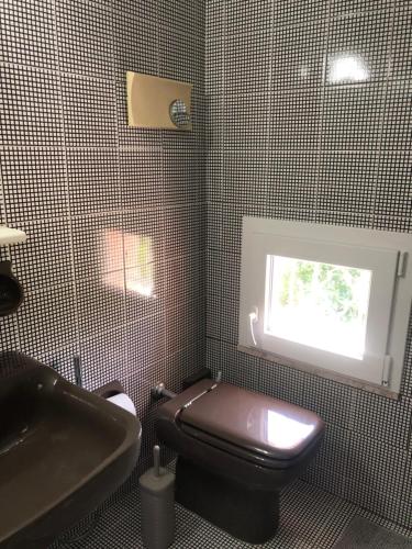 baño con aseo y lavabo y ventana en Barbara, en Santa Maria di Scacciano