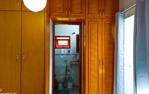 uma casa de banho com WC e armários de madeira em casa Encantadora em Florianópolis