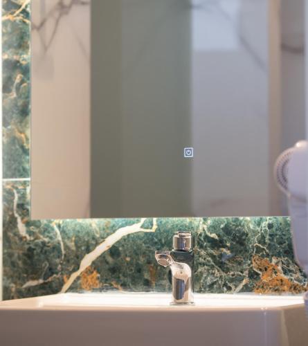 a bathroom sink with a faucet in front of a mirror at Aetherion Studios & Suites in Kalyves Poligirou