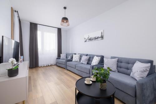 ein Wohnzimmer mit einem blauen Sofa und einem Tisch in der Unterkunft Osiedle Avia Harmonious Apartment with Balcony & Parking Cracow by Renters Prestige in Krakau