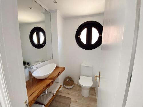 a bathroom with a sink and a toilet and two mirrors at Apartamento Nuria Comillas in Comillas