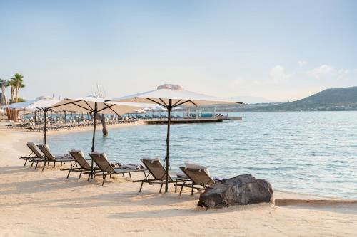 een groep stoelen en parasols op een strand bij Biblos Resort Alaçatı in Alacati