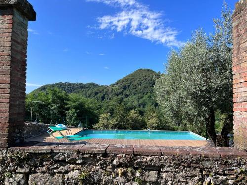 una piscina con una montaña en el fondo en Podere il Giardino - Casale Rustico degli Ulivi con piscina e parco - Lucca, en Loppeglia