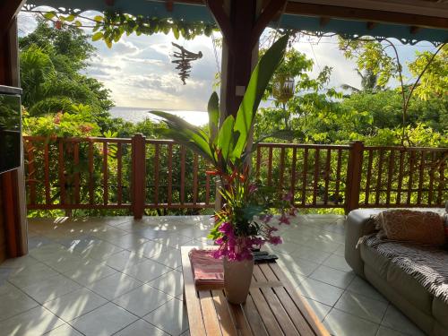 a porch with a couch and a plant at Villa Nature caraïbe lodge, vue mer, piscine privée in Deshaies